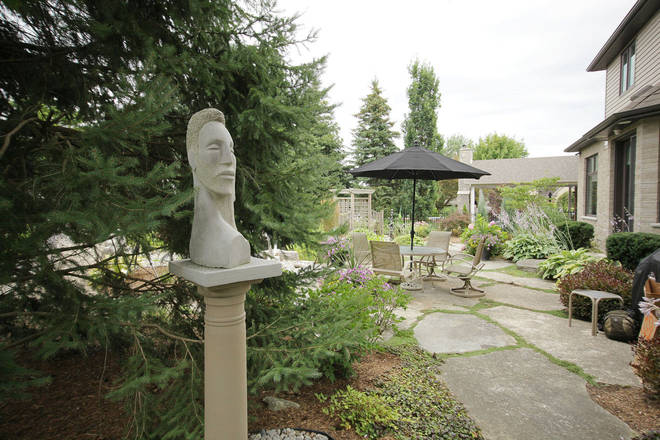 Garden art. Stone sculpture in its backyard setting. Daphne and Apollo. Limestone. 22in x 14in x 71/2in.