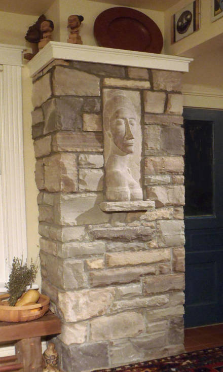 Custom hand-hewn stone chimney with hand-sculpted stone relief of a woman's bust. A stone masonry, custom stonework and sculpture project.