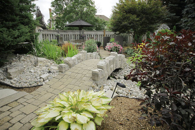 Hand-hewn stone bridge, stone landscape and paver pathway.
