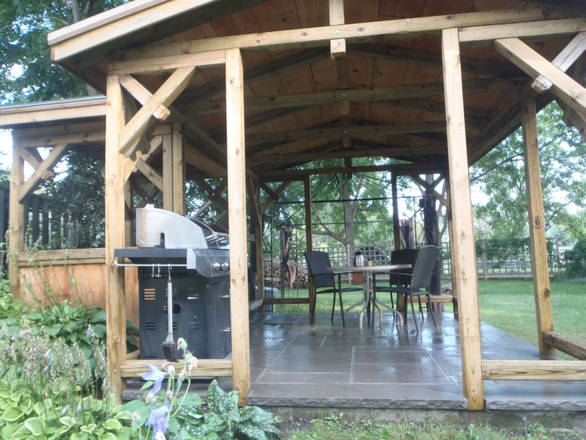 Square-cut flagstone patio. Timber-framed covered room.